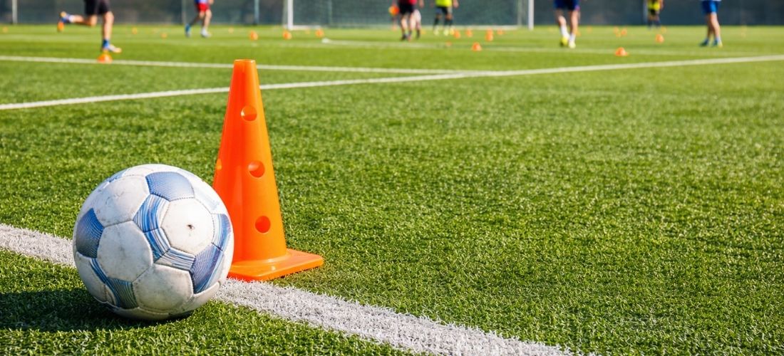 Fußball-Trainingssituation auf einem Kunstrasenplatz.