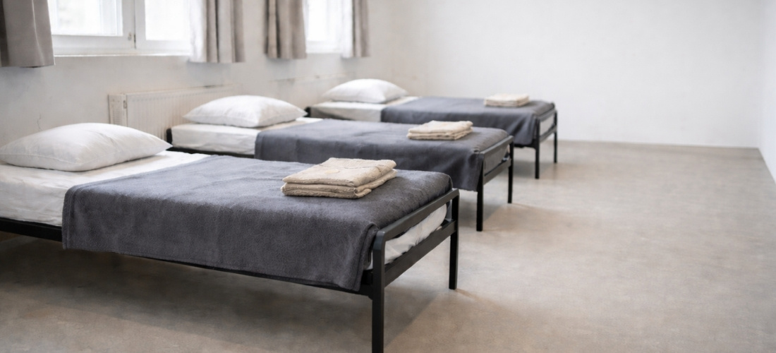 KI-generiertes Symbolbild einer Übernachtungsstelle in einem schlichten Zimmer mit Betten